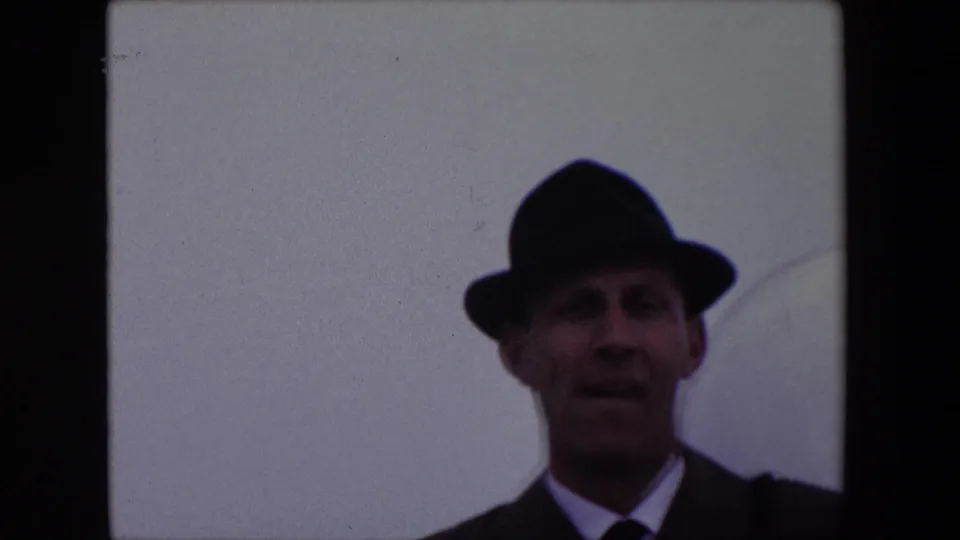 The 1967 Calais frame shows the same adult white man in a fedora and formal clothing looking toward the camera, with his mouth slightly open as if speaking.