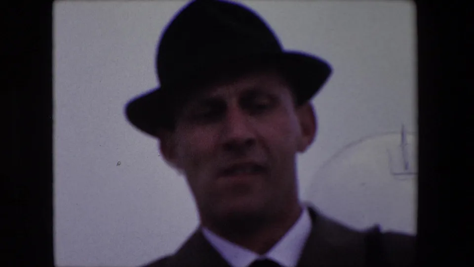 The final 1967 Calais frame gives a closer, soft-focus view of the adult white man in a dark fedora, suit, white shirt, and tie looking toward the home-movie camera.