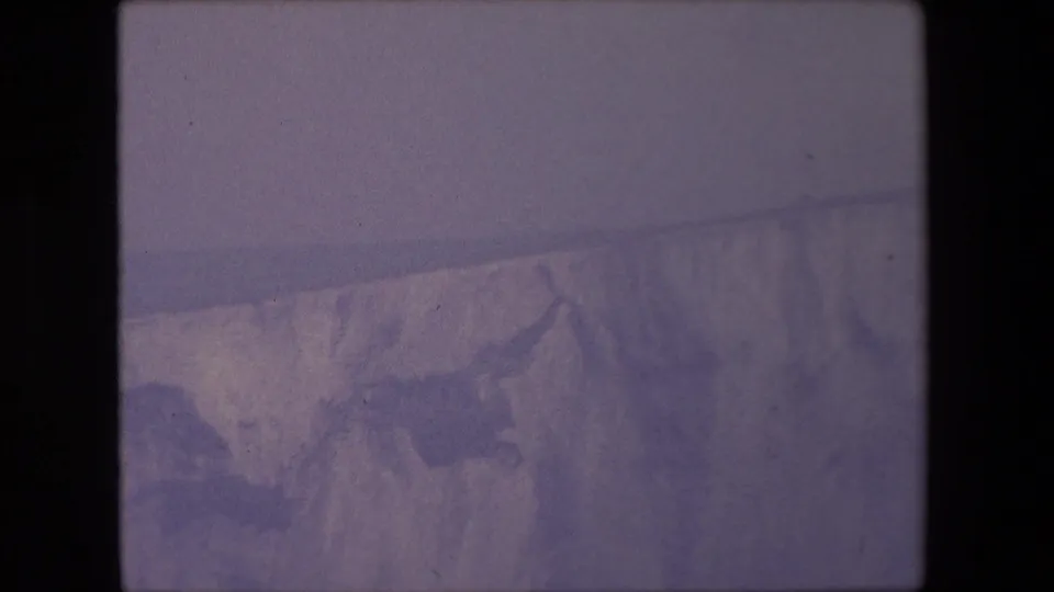 The final frame shows a broad, grainy view of a pale cliff or coastal landform near Calais, softened by haze and the color shift of 8mm film.