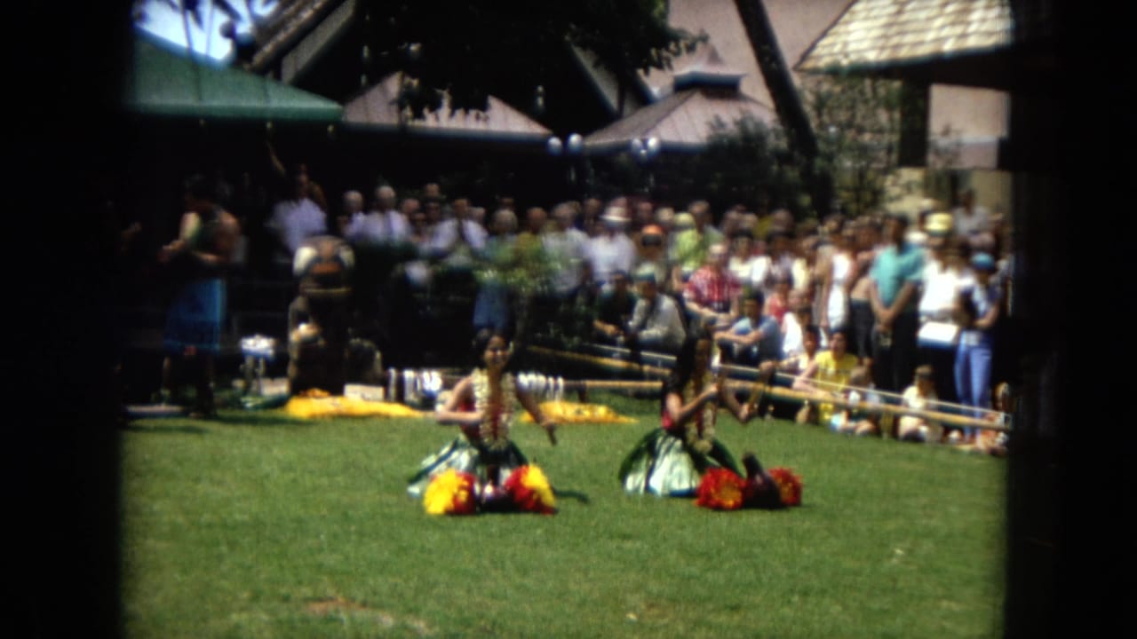 Dancers on grass with a crowd watching and musicians in the background.