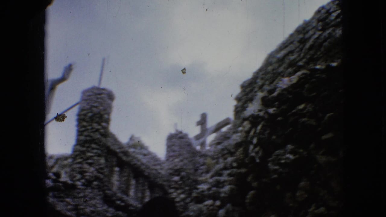Stone towers and a small cross-like shape with the robed statue partly visible.