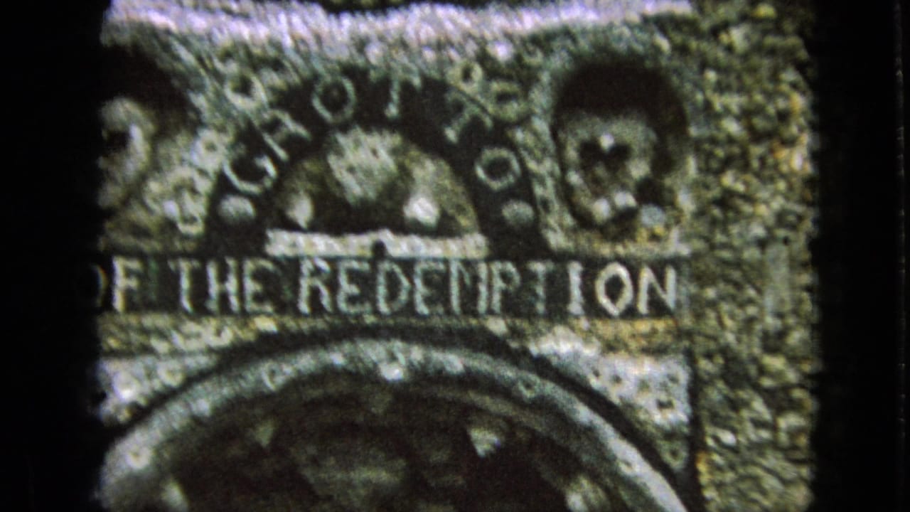 Close 8mm view of carved stonework at the Grotto of the Redemption, with large lettering and decorative relief details visible in soft focus.