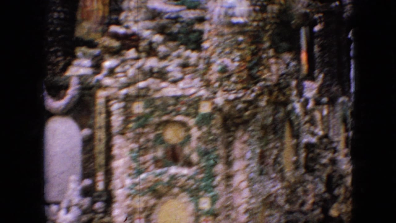 Stone wall with arched recesses, small religious figures, and a dark central post.