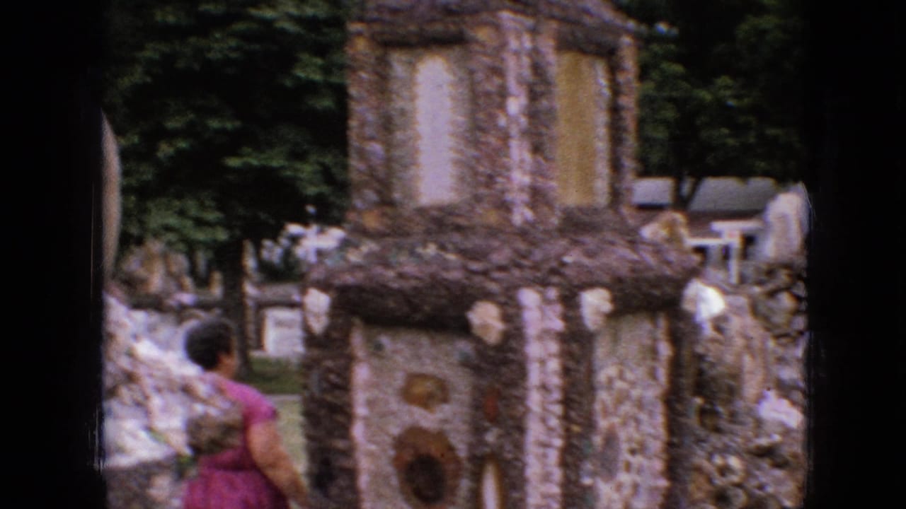 Visitors walk near pebble-covered stone structures and trees.
