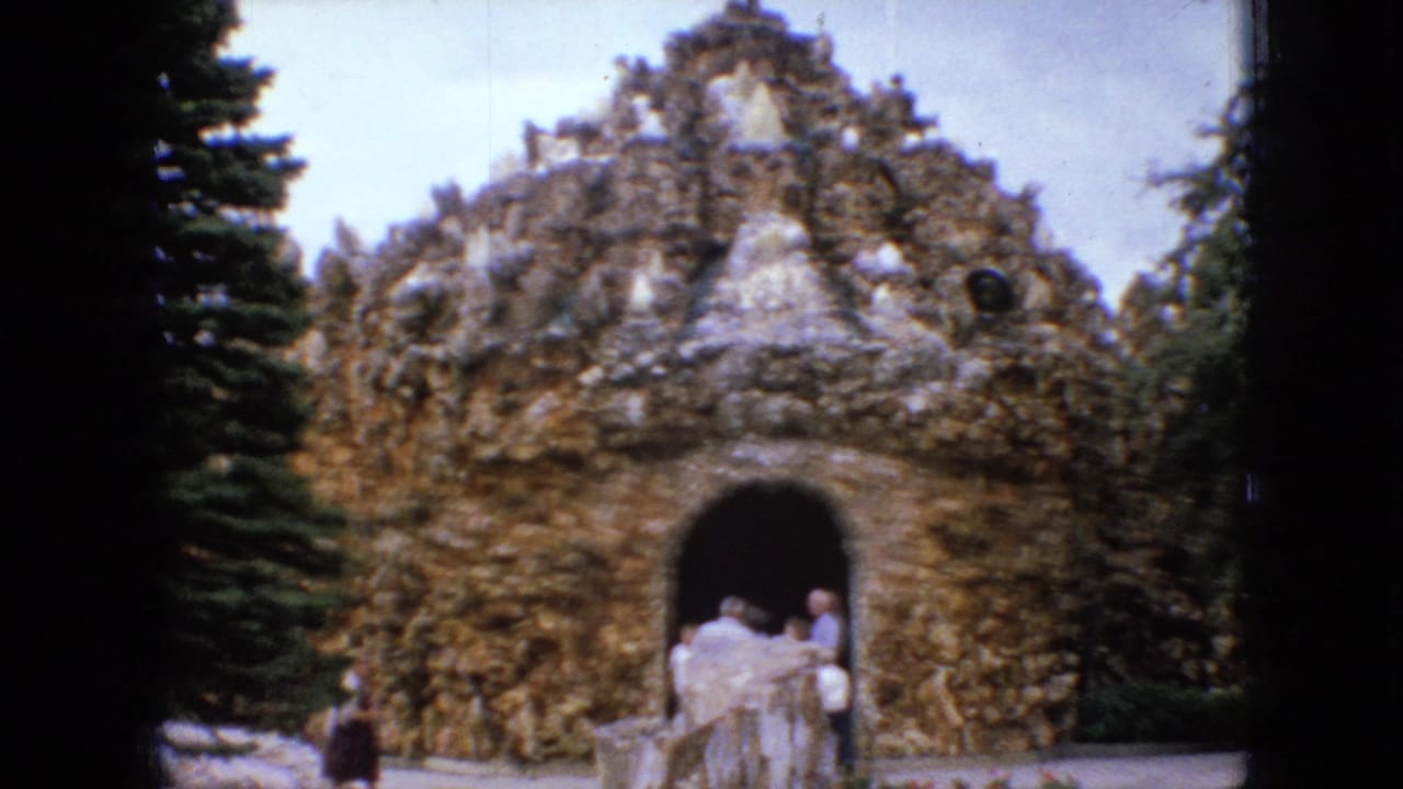 Castle-like rock grotto with an arched doorway and people standing nearby.