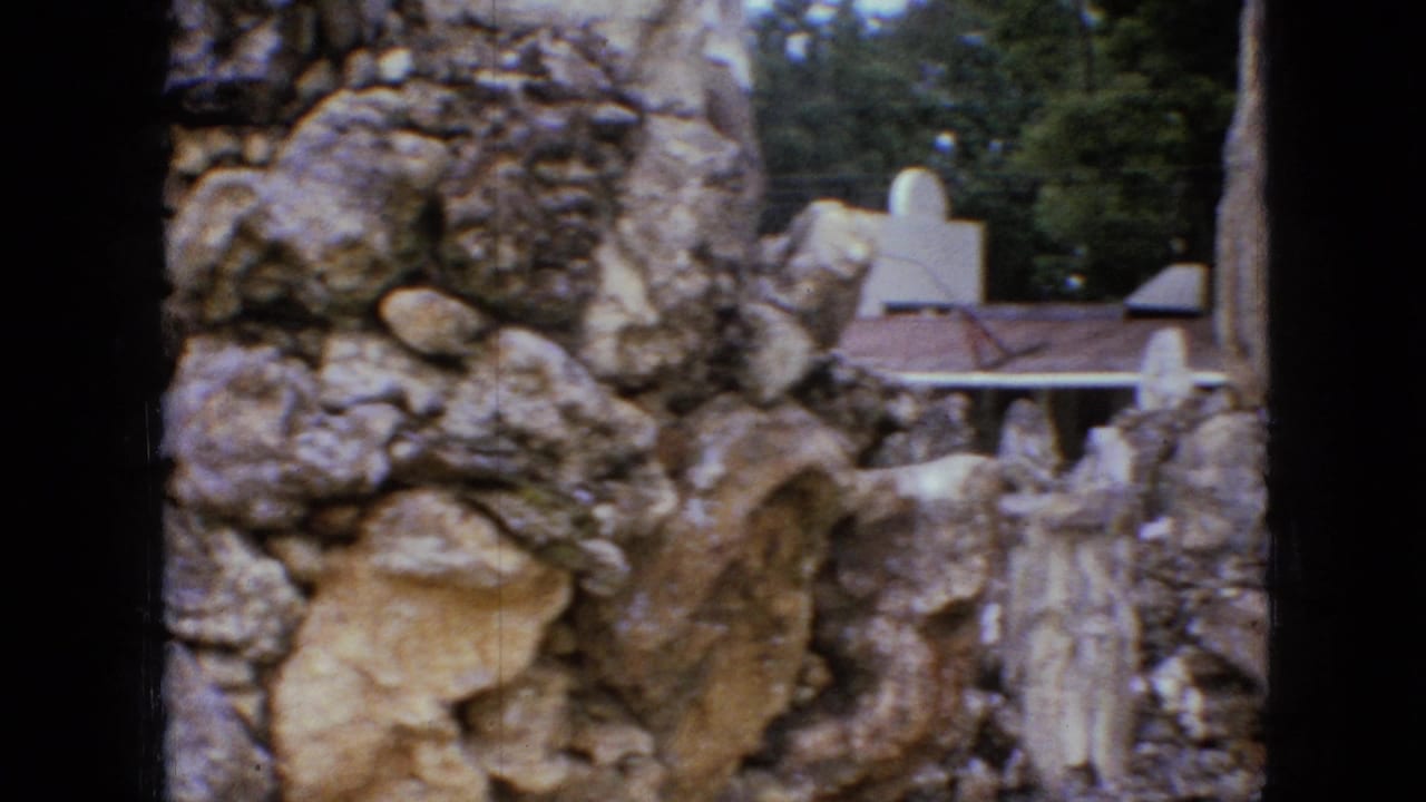 Close view of rough stonework with a small roofed structure partly visible at right.