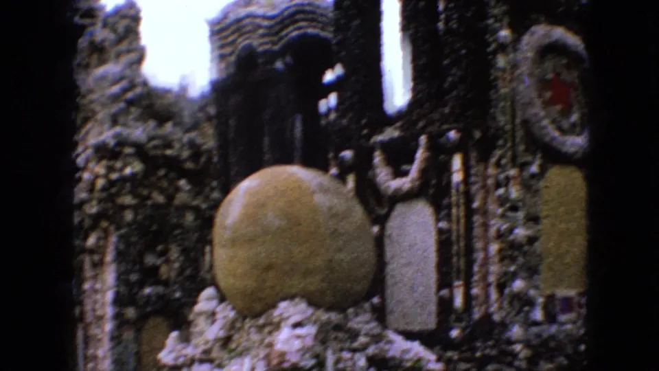 1967 Iowa 8mm frame looking into a narrow constructed stone passage with a large spherical stone feature and textured walls on both sides.