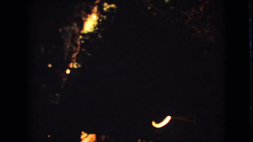 1967 Iowa 8mm frame with the decoration receding into shadow and a small curved warm light near the lower edge.