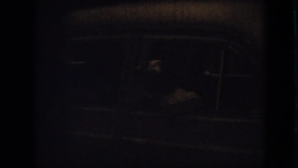 The final 1967 Iowa home-movie frame is dark and blurry, with faint lines and small highlights suggesting a low-light vehicle or interior view.