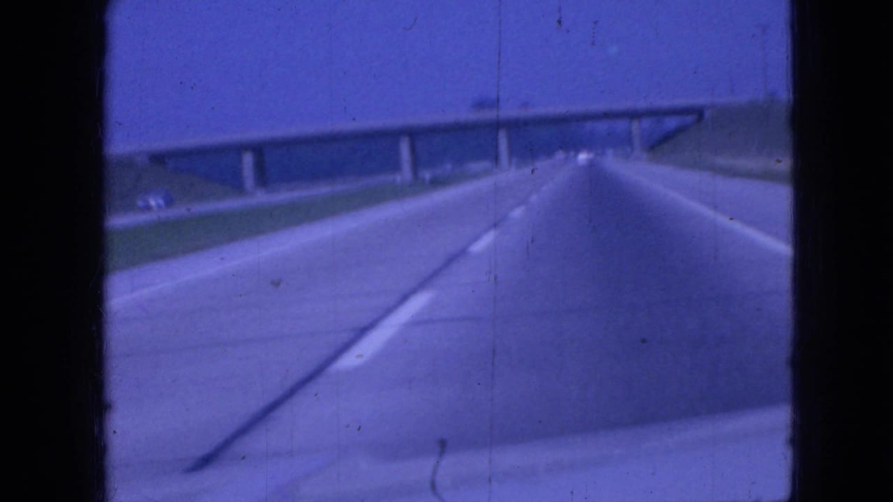 Highway lanes continue toward an overpass with grassy embankments on both sides.