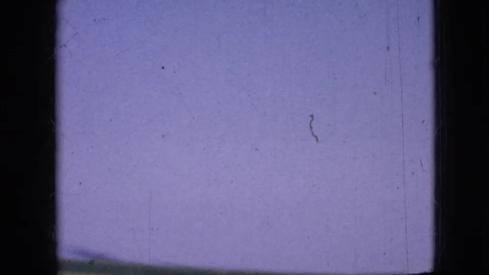 A 1967 Iowa 8mm frame with purple-blue sky and a thin rural horizon line, seen through heavy film gate borders and surface marks.
