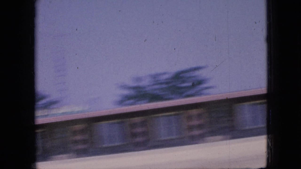 Motion-blurred low roadside building or structure beneath a pale sky.