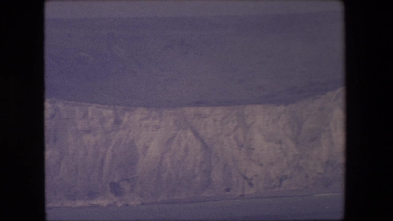 Distant cliff face stretching along the shoreline beside dark water.