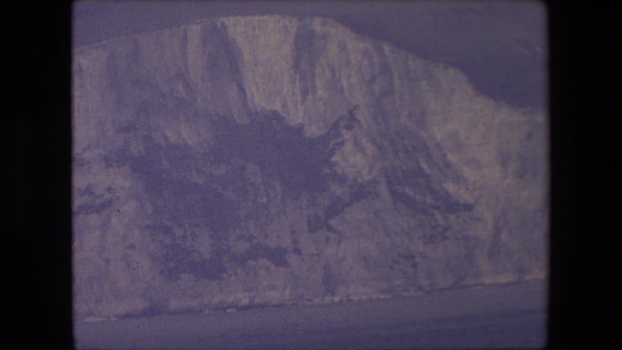 Pale chalk cliffs above a dark strip of sea under a hazy sky.