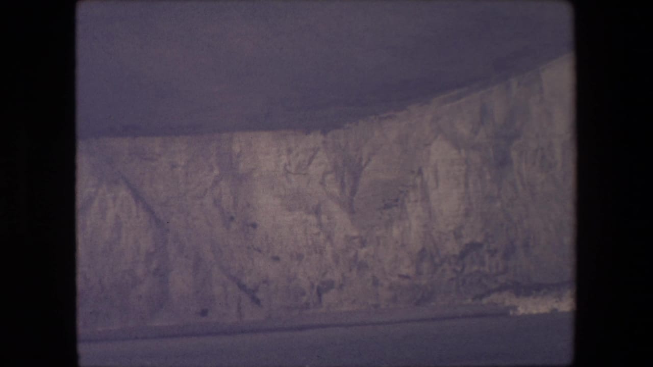 Ice cliffs above dark water with black film border visible.