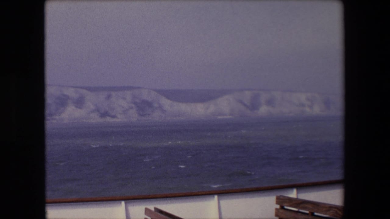 Distant chalk cliffs and rough water viewed from a vessel.