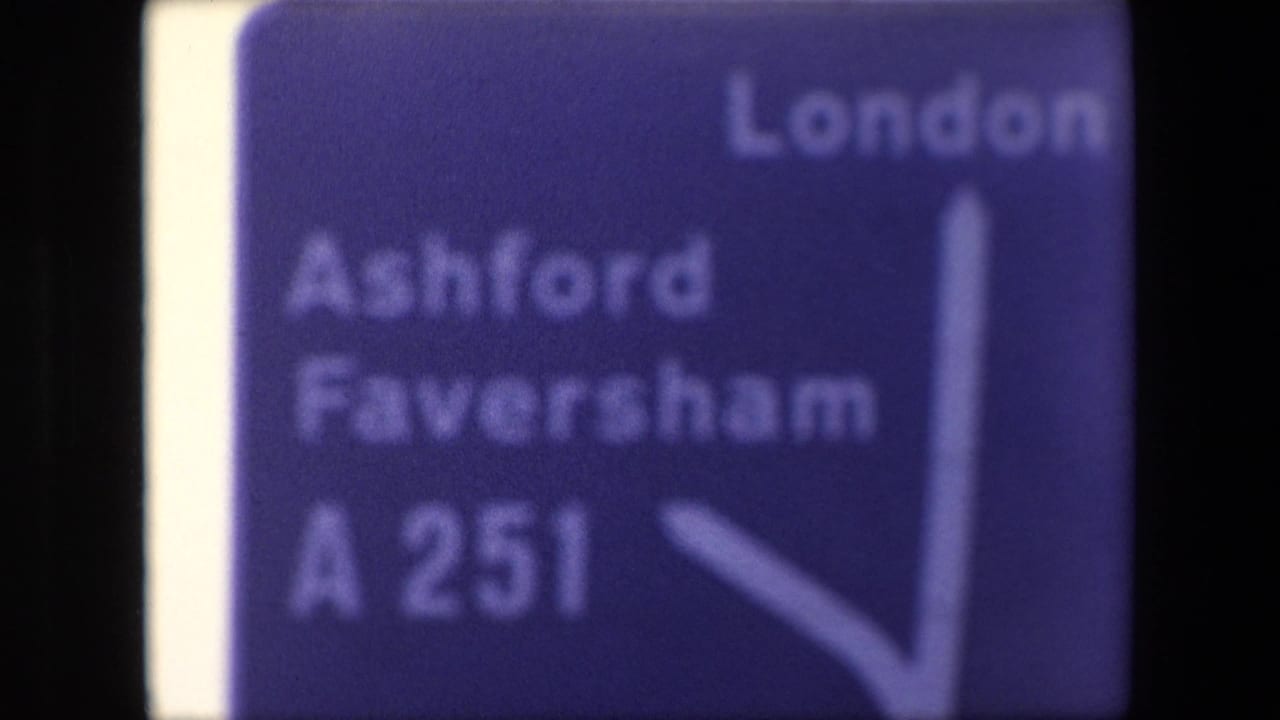 Blue direction sign with London, Ashford, Faversham, A251, and a white arrow.