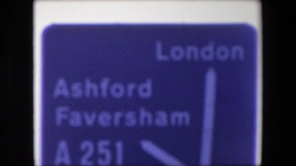 Close 8mm view of a 1967 British road sign showing London, Ashford Faversham, A251, and a white directional arrow.