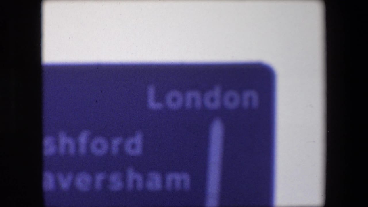 Partial blue directional sign with London text and an upward arrow visible.