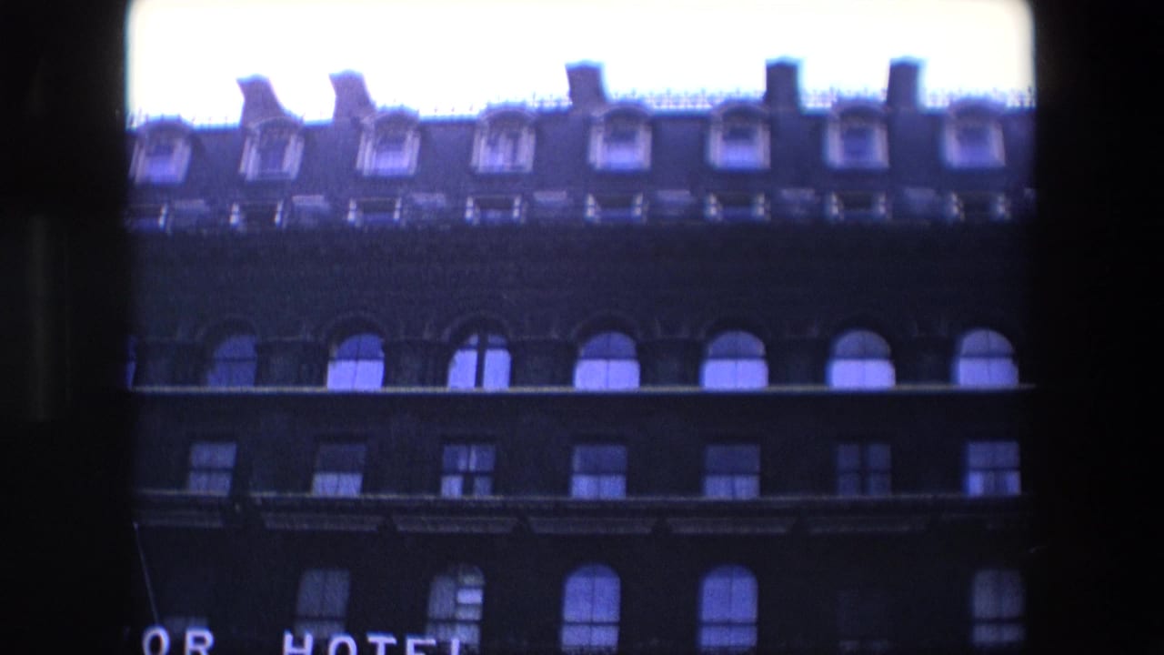 Low-angle view of a dark hotel facade with arched windows and a partial illuminated sign.