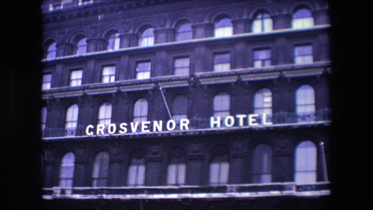 Upper facade of the Grosvenor Hotel with illuminated sign and arched windows.