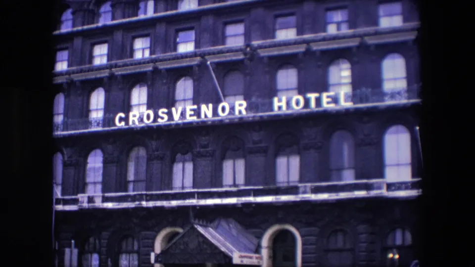 1967 London frame of the Grosvenor Hotel facade, with the illuminated name, rows of windows, and the entrance canopy partly visible at street level.