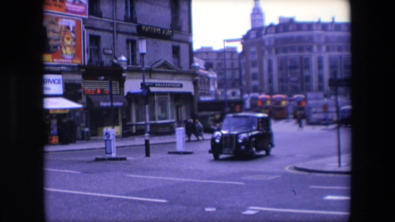 Black taxi driving through a London street with buses and shopfronts in the background.