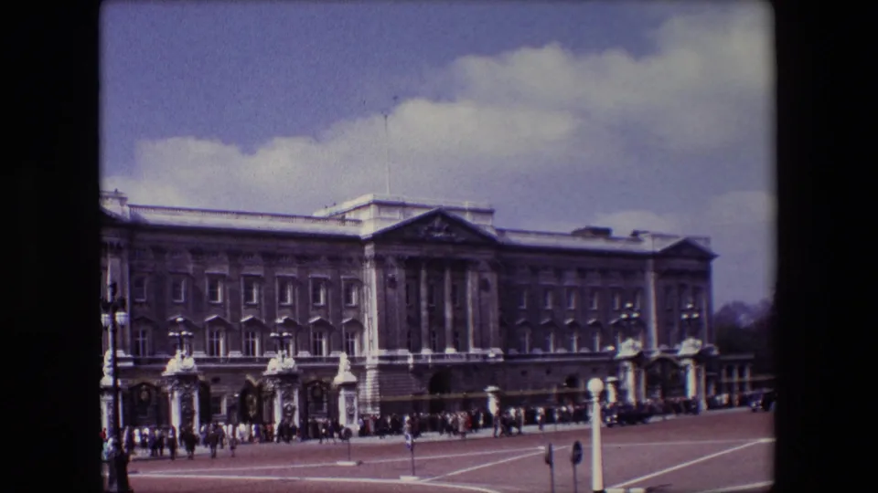 Buckingham Palace in London appears in a soft 8mm frame as tourists line the gates and move across the open forecourt in 1967.