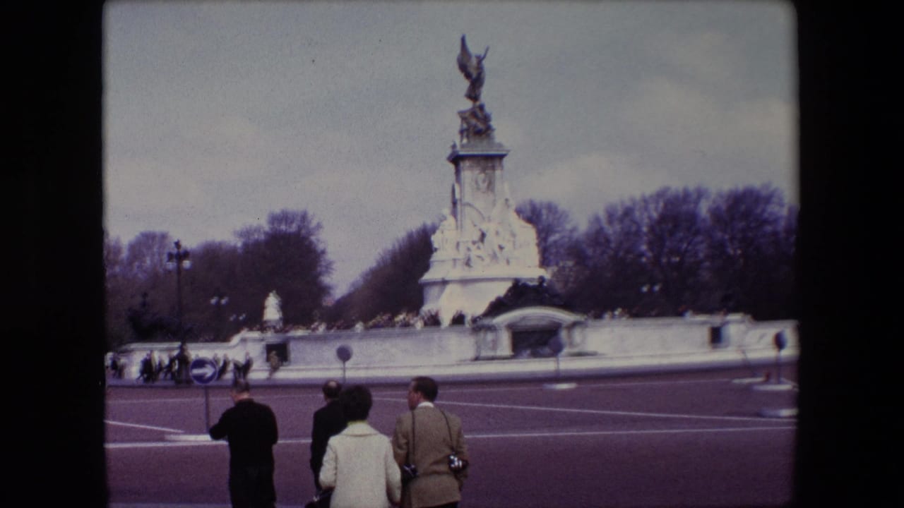 Pedestrians stand near the curb facing the Victoria Memorial across the road.