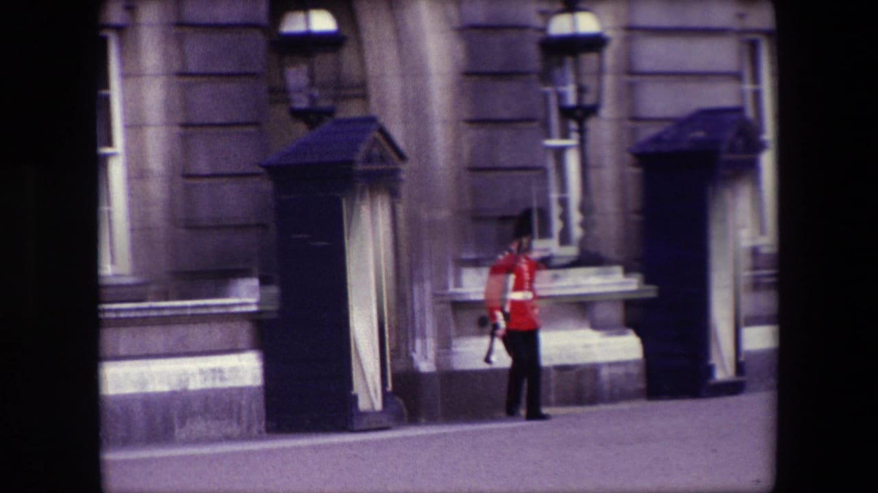 1967 London 8mm frame showing a British royal guard in a red tunic near a black sentry box, stone facade, sash window, and ornate lamppost.