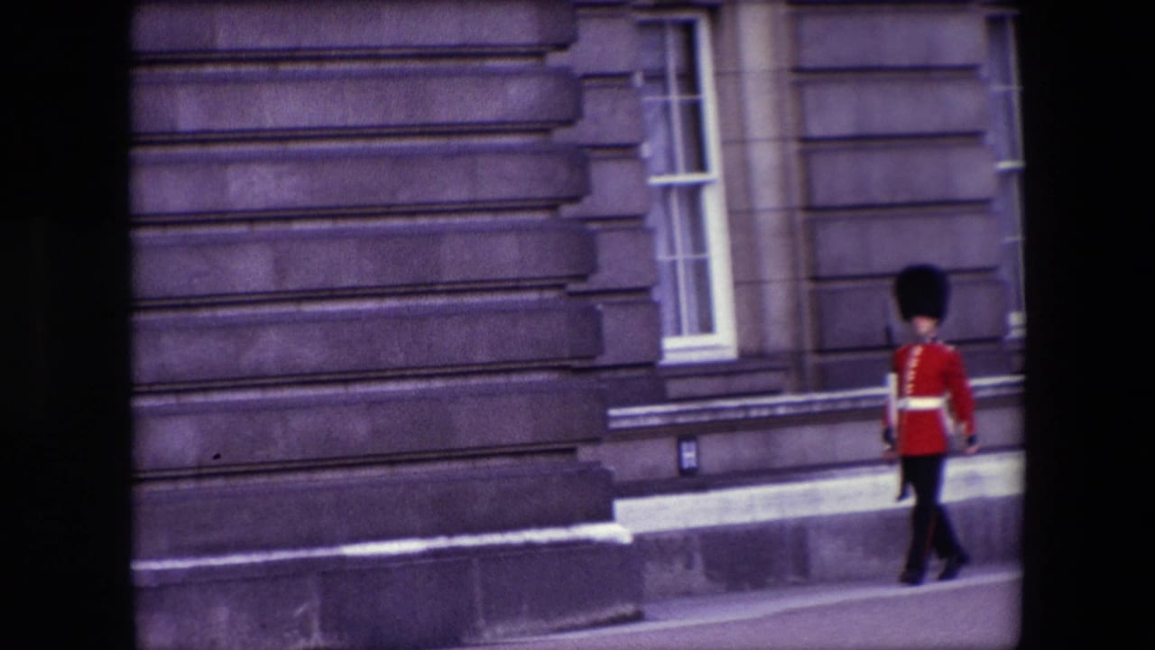 Red-coated guard marching near the edge of a paved walkway.