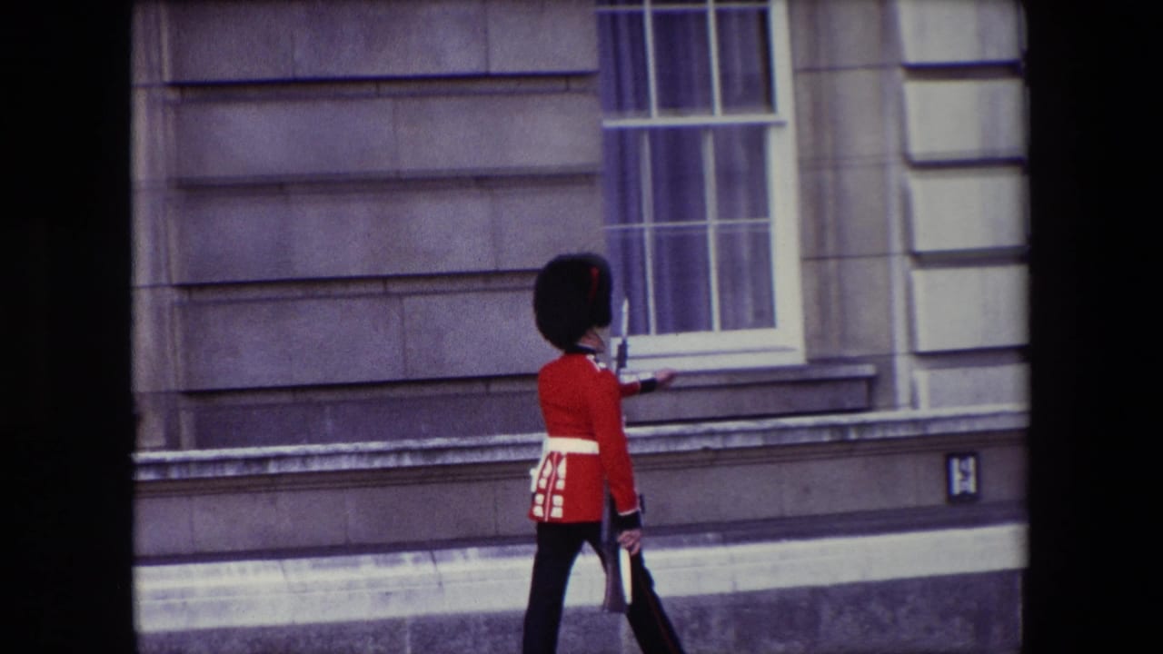 Queen's Guard in red tunic marching past a stone building facade.