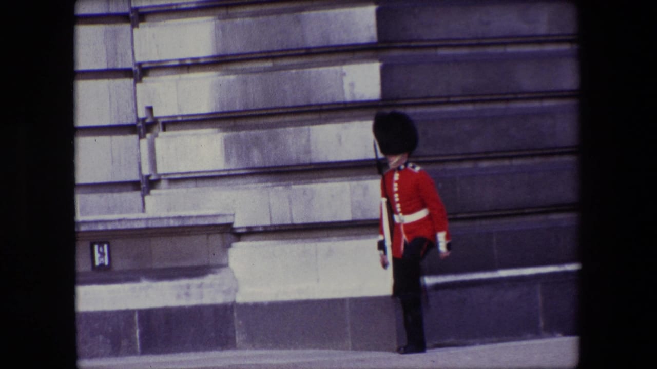Palace guard in red tunic standing near a stone wall and window.