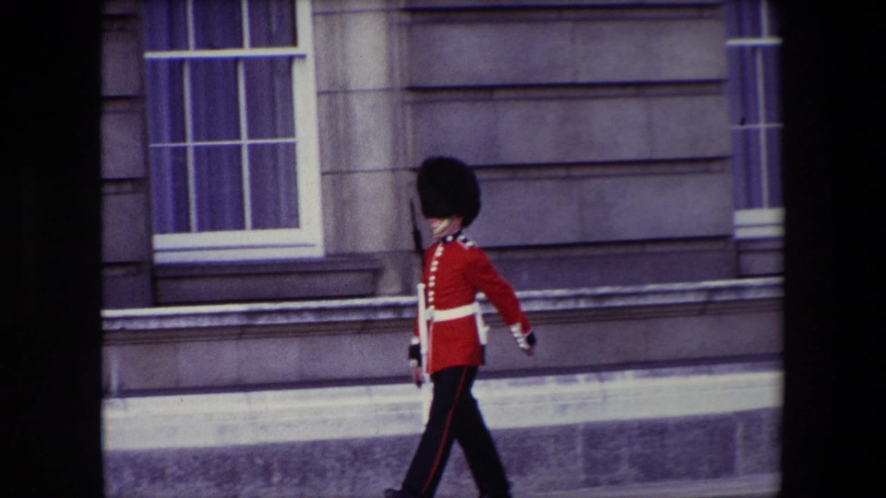A Queen's Guard in red tunic and tall black hat marches along a pavement in London, England, supported by the supplied 1967 metadata.