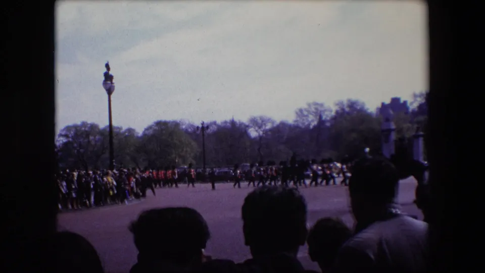 The closing frame shows a visitor's view of soldiers in red uniforms marching through a London ceremonial space in 1967, with spectators and foreground silhouettes framing the scene.