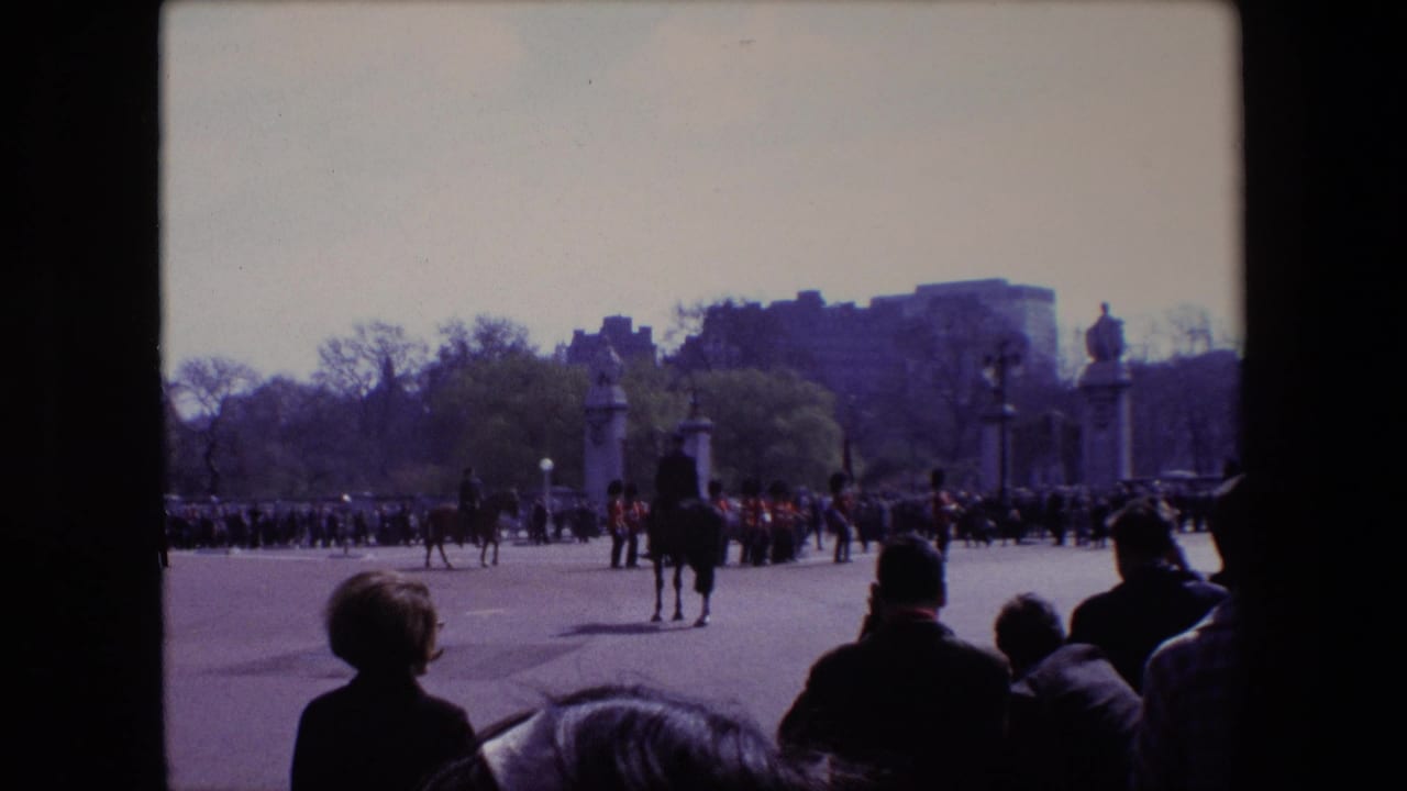 Spectators watch mounted riders and marching guards across an open parade ground.