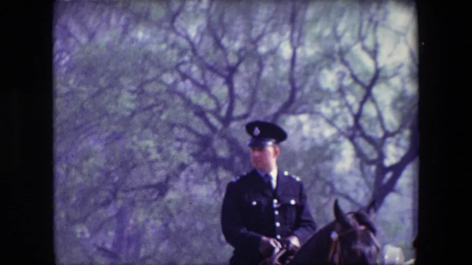 A mounted uniformed officer appears on horseback in a park-like London setting, with bare trees and soft 8mm color from the supplied 1967 footage.