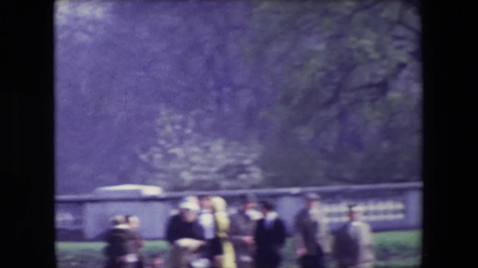 A small group of spectators stands near a stone balustrade or wall in the London parade setting, partially blurred by the 8mm home-movie capture.