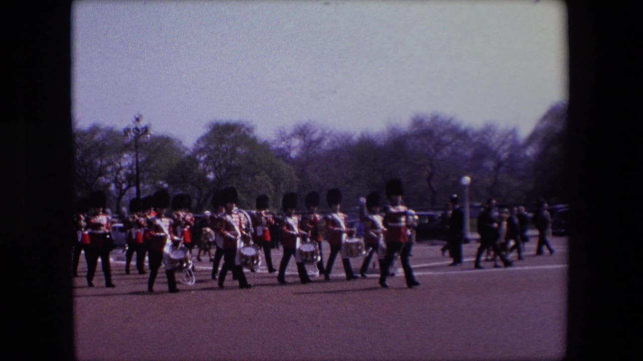 Marching band in red uniforms crosses an open roadway with drums and brass visible.