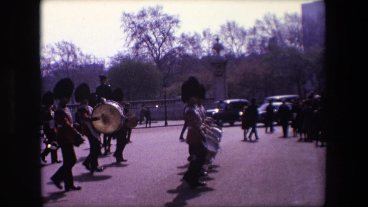 Guards in red uniforms march past with drums on a London street.