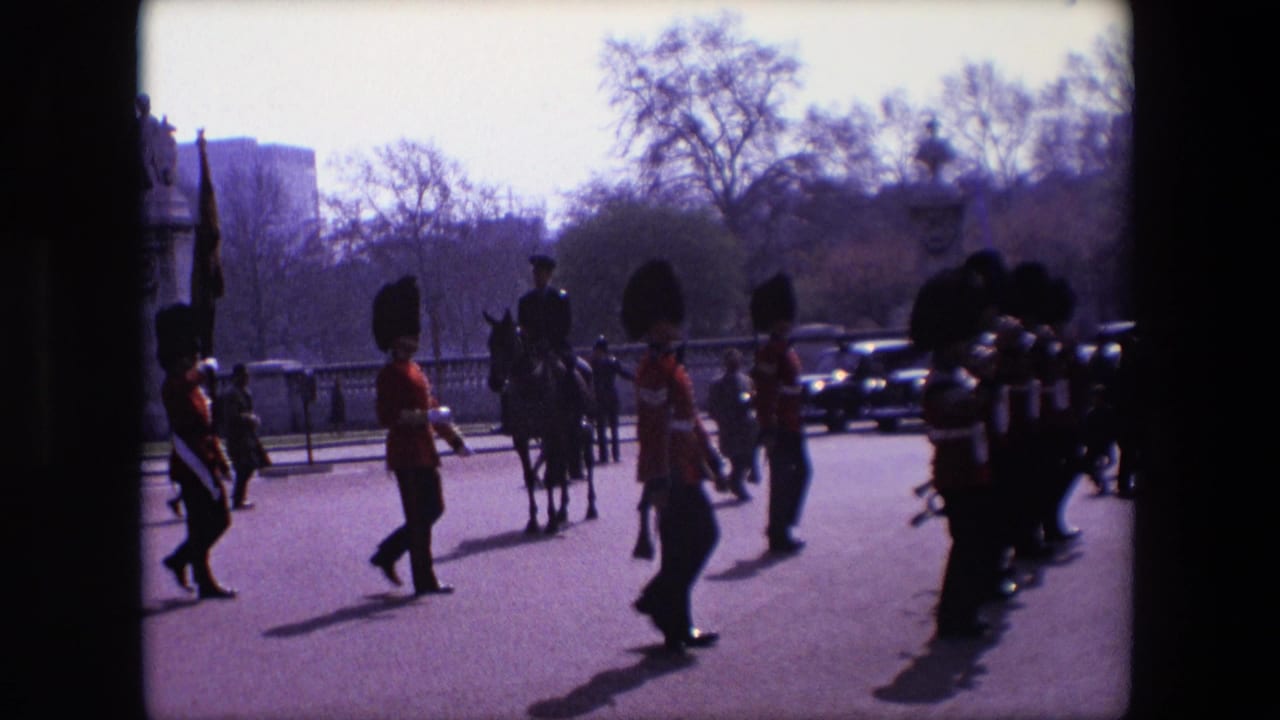 A mounted officer and Guards pass through a roadway with pedestrians and cars in the background.