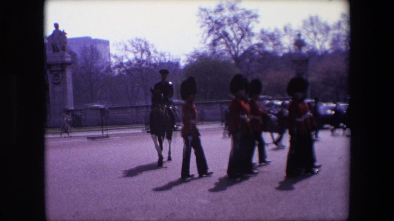 A mounted uniformed figure stands near marching guards during a street procession.
