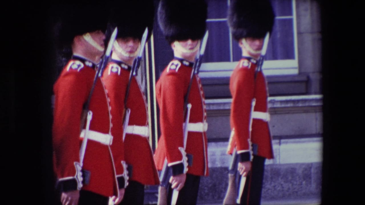 1967 London frame of several Buckingham Palace guards in ceremonial uniforms standing in profile with rifles and bayonets beside a stone exterior.