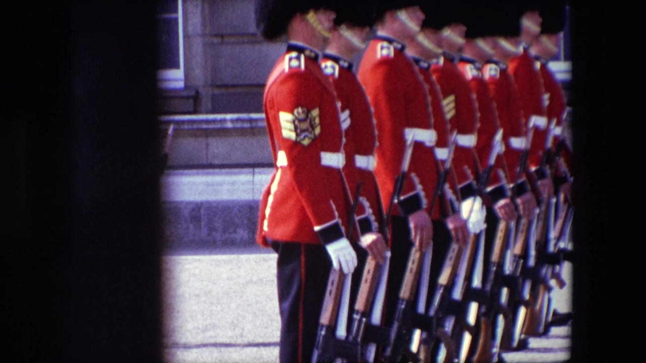 Uniformed guards in red tunics stand in a row holding rifles beside a stone building.