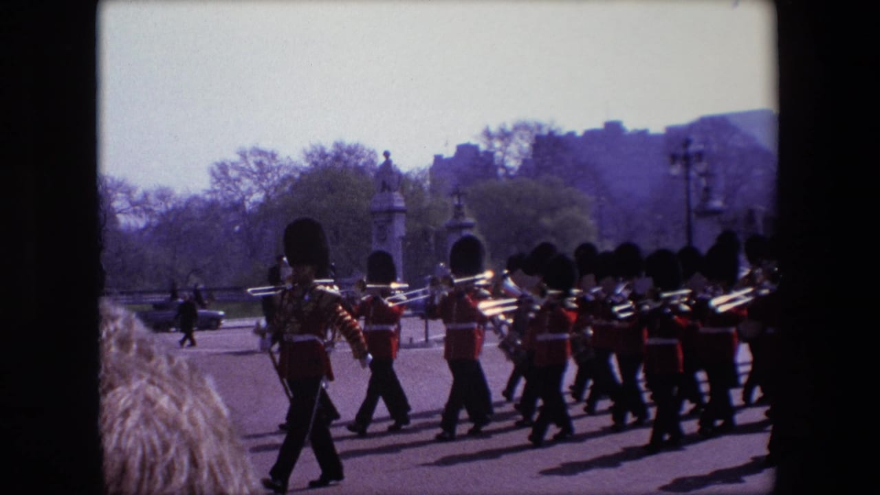 Marching band in guard uniforms moves past the camera with trombones visible.