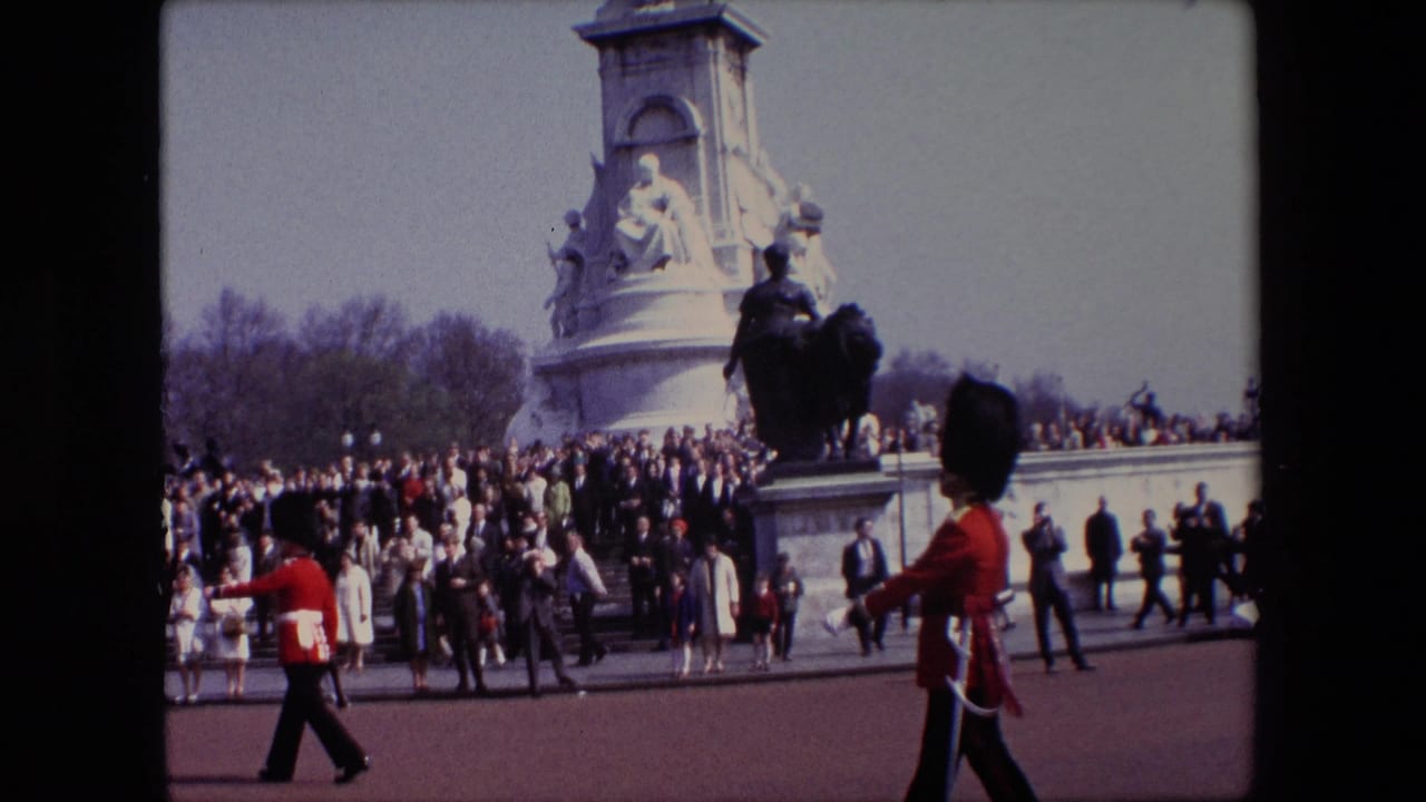 Ceremonial soldiers march past a crowd near a large stone monument.
