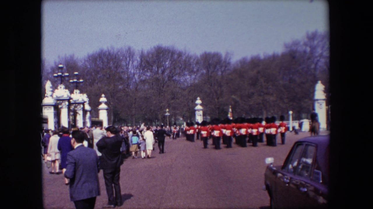 Crowd stands near palace gates as guards form a line across the forecourt.