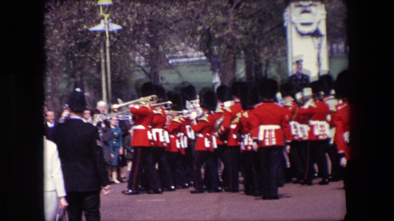Red-uniformed marching band seen from behind on a crowded street.