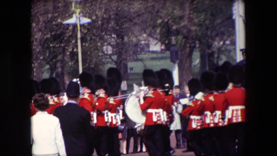 A rear view of the 1967 London parade shows the marching band continuing past spectators, with a large drum, brass instruments, and street furniture visible.