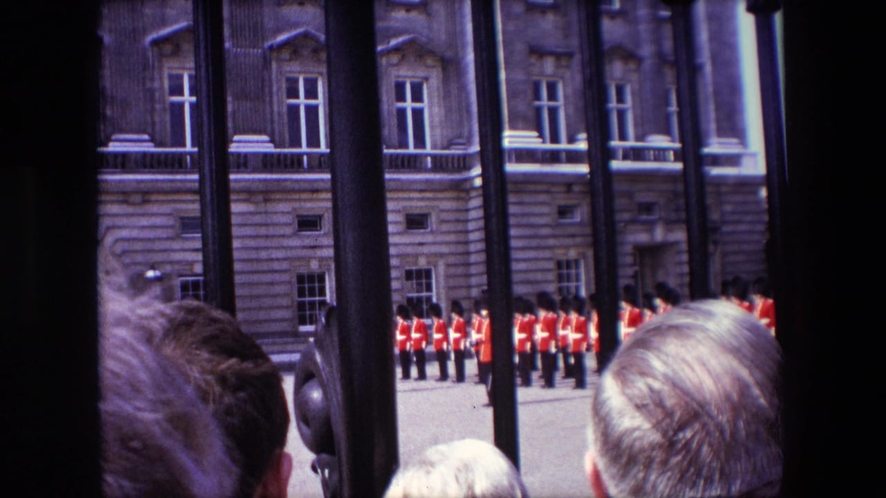Red-coated guards stand near a stone palace facade behind iron railings.